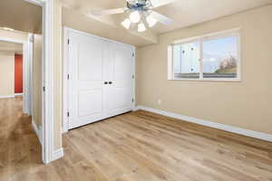 Unfurnished bedroom with light wood-style floors, a closet, and ceiling fan
