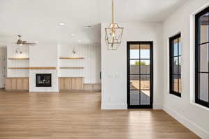 Unfurnished living room featuring light wood-style flooring, a glass covered fireplace, recessed lighting, and ceiling fan