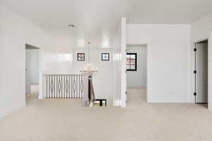 Corridor with light carpet, an upstairs landing, and a chandelier