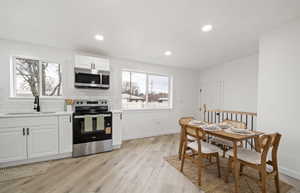 Kitchen featuring stainless steel appliances, white cabinets, light wood-style floors, backsplash, and recessed lighting