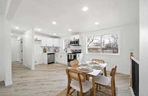 Dining room with light wood-style flooring and recessed lighting