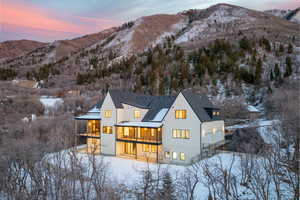 Snow covered back of property featuring a balcony, a mountain view, stucco siding, and a garage