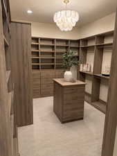Walk in closet with light carpet and a chandelier