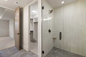 Bathroom featuring carpet flooring, a shower stall, a walk in closet, tile patterned flooring, and recessed lighting