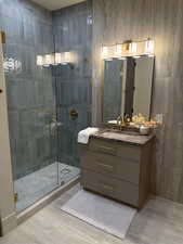 Bathroom featuring a stall shower, vanity, and light wood-type flooring