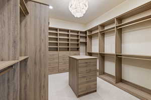 Primary Bedroom Walk in closet featuring an alabaster chandelier and built-in laundry.