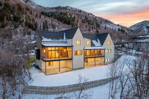 Snow covered house featuring a balcony, a mountain view, roof with shingles, and a patio