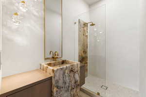 Guest bathroom featuring white oak cabinetry, a free standing sink make from Patagonia quartzite, a walk in shower in artisanal plaster, highlighted with a slab of Patagonia quartzite