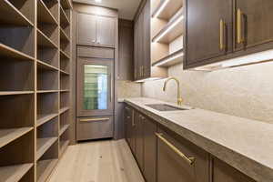 Butler's Pantry with floor to ceiling shelving, a Sub Zero Beverage refrigerator and freezer, pebble ice maker, dish washer and sink. With white oak cabinetry, Mojave quartzite countertops and full height backsplash.