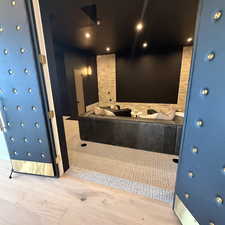 Full bathroom with recessed lighting, a garden tub, and light wood-style floors