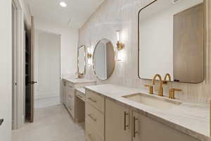 Bathroom featuring two vanities, recessed lighting, tasteful backsplash, and tile walls
