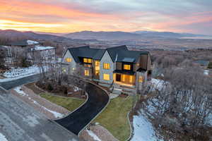 View of front of house featuring a standing seam roof, stone siding, a yard, a mountain view, and a balcony