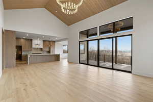 Unfurnished living room featuring a chandelier, a vaulted wood ceiling, light wood-style floors, and a mountain view