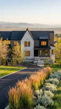 View of front of property featuring stone siding, a mountain view, a front lawn, and a standing seam roof