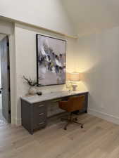 Home office with light wood-type flooring and vaulted ceiling