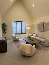 Living area featuring a high ceiling, carpet flooring, and recessed lighting