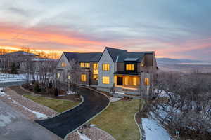Contemporary home featuring a standing seam roof, stone siding, a front lawn, and a balcony