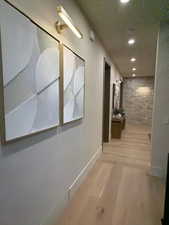 Corridor featuring a textured ceiling, recessed lighting, and light wood-style floors