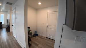 Corridor featuring light wood-style floors, recessed lighting, and arched walkways