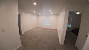 Unfurnished room with dark colored carpet and recessed lighting
