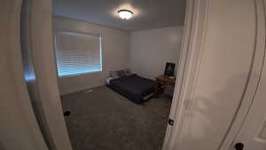Unfurnished bedroom with dark carpet and a textured ceiling