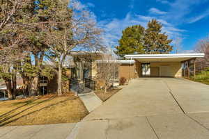 Mid-century home with driveway, a carport, and brick siding