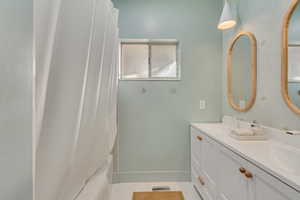 Full bathroom with double vanity and shower / tub combo with curtain