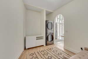 Laundry room with light wood-style floors and stacked washing machine and dryer