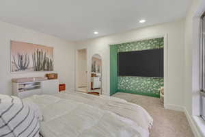 Carpeted bedroom featuring arched walkways and recessed lighting