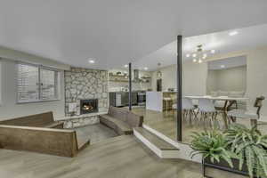 Living room featuring light wood-type flooring, a chandelier, and a fireplace
