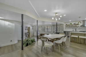 Dining area with light wood-type flooring, a wood stove, a chandelier, and recessed lighting