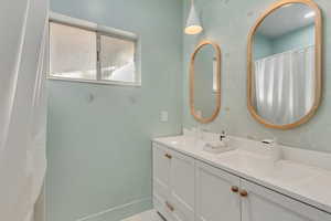 Full bath with double vanity, curtained shower, and wallpapered walls