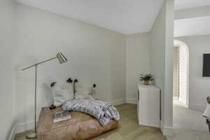 Bedroom with light wood-type flooring and arched walkways