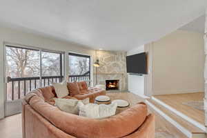 Living area with a premium fireplace, light wood-style flooring, and a textured ceiling