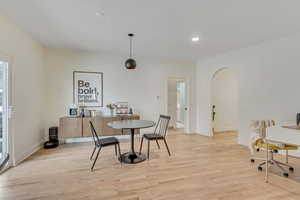 Dining room featuring light wood-type flooring, arched walkways, and recessed lighting