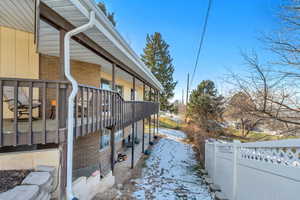 View of snowy exterior featuring brick siding and a patio area