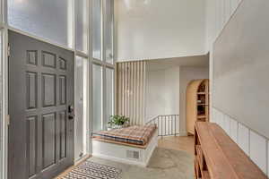 Foyer with arched walkways, light wood-type flooring, and a high ceiling