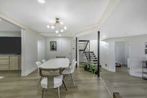 Dining room with light wood finished floors, a chandelier, stairway, and recessed lighting