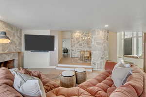 Living room with a stone fireplace and wood finished floors
