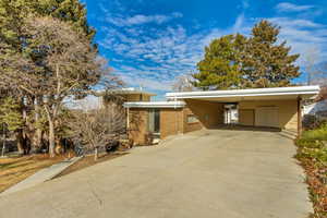 View of side of property featuring concrete driveway, an attached carport, and brick siding