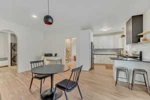 Dining room with light wood-style flooring, arched walkways, and stacked washer / dryer