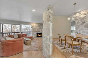 Living room with a stone fireplace, light wood-style floors, and recessed lighting
