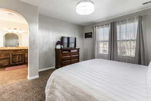 Carpeted bedroom featuring tile patterned floors, arched walkways, and suspended lighting
