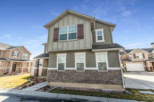 Craftsman inspired home featuring board and batten siding, stucco siding, a shingled roof, and stone siding