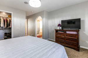 Carpeted bedroom featuring arched walkways and a walk in closet