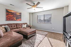 Carpeted living room featuring baseboards and ceiling fan