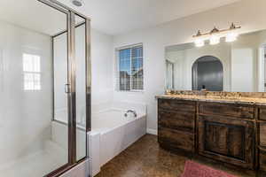 Full bath featuring vanity, a stall shower, dark tile patterned floors, and a bath
