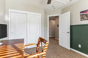 Carpeted office featuring attic access and ceiling fan