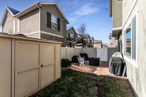 Fenced backyard featuring a shed, a patio area, a gate, and a residential view