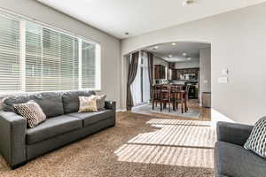 Living room with arched walkways, recessed lighting, and light tile patterned flooring